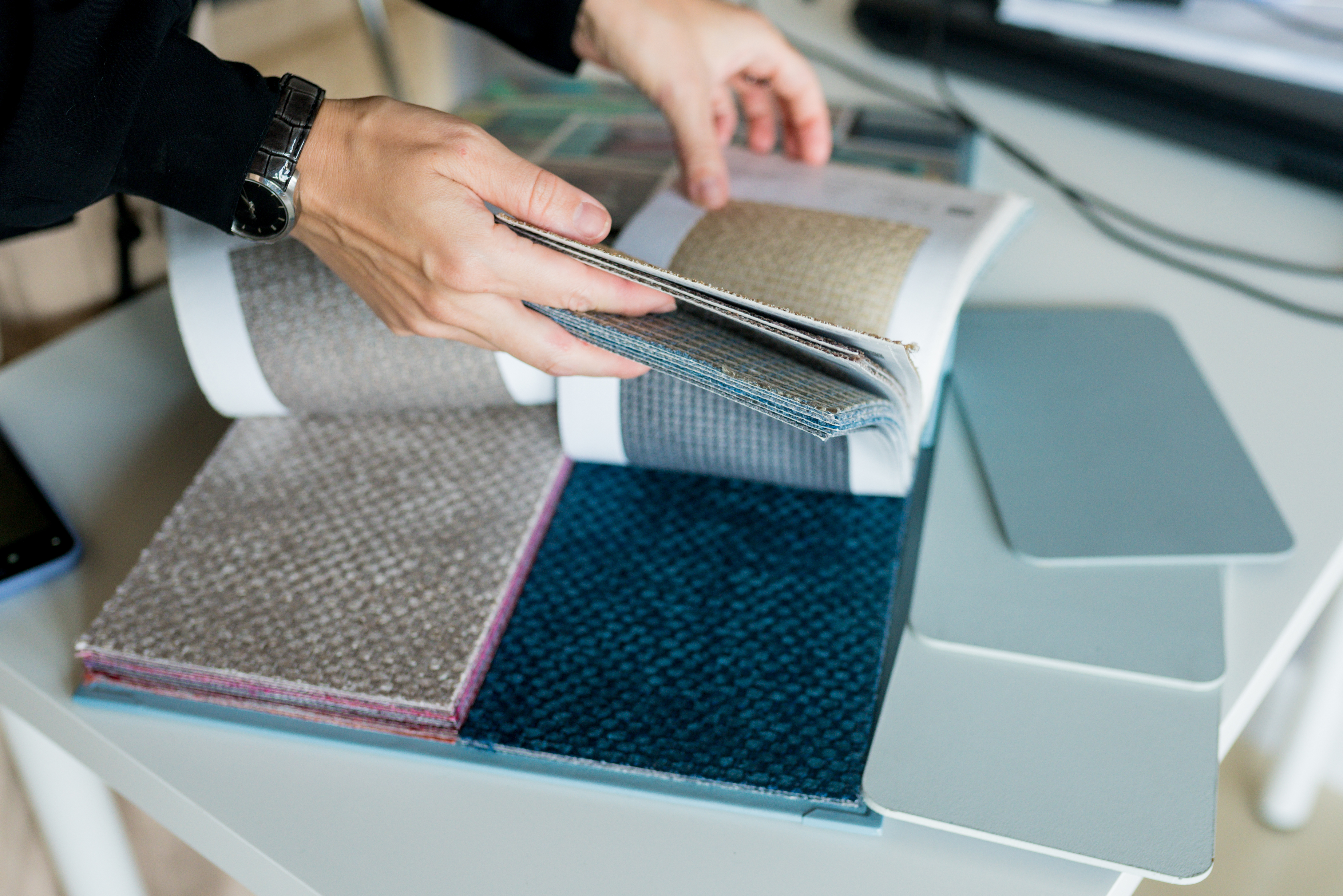 Close-up woman choosing fabrics swatches for sofa in store. Interior designer looking materials for home renovation